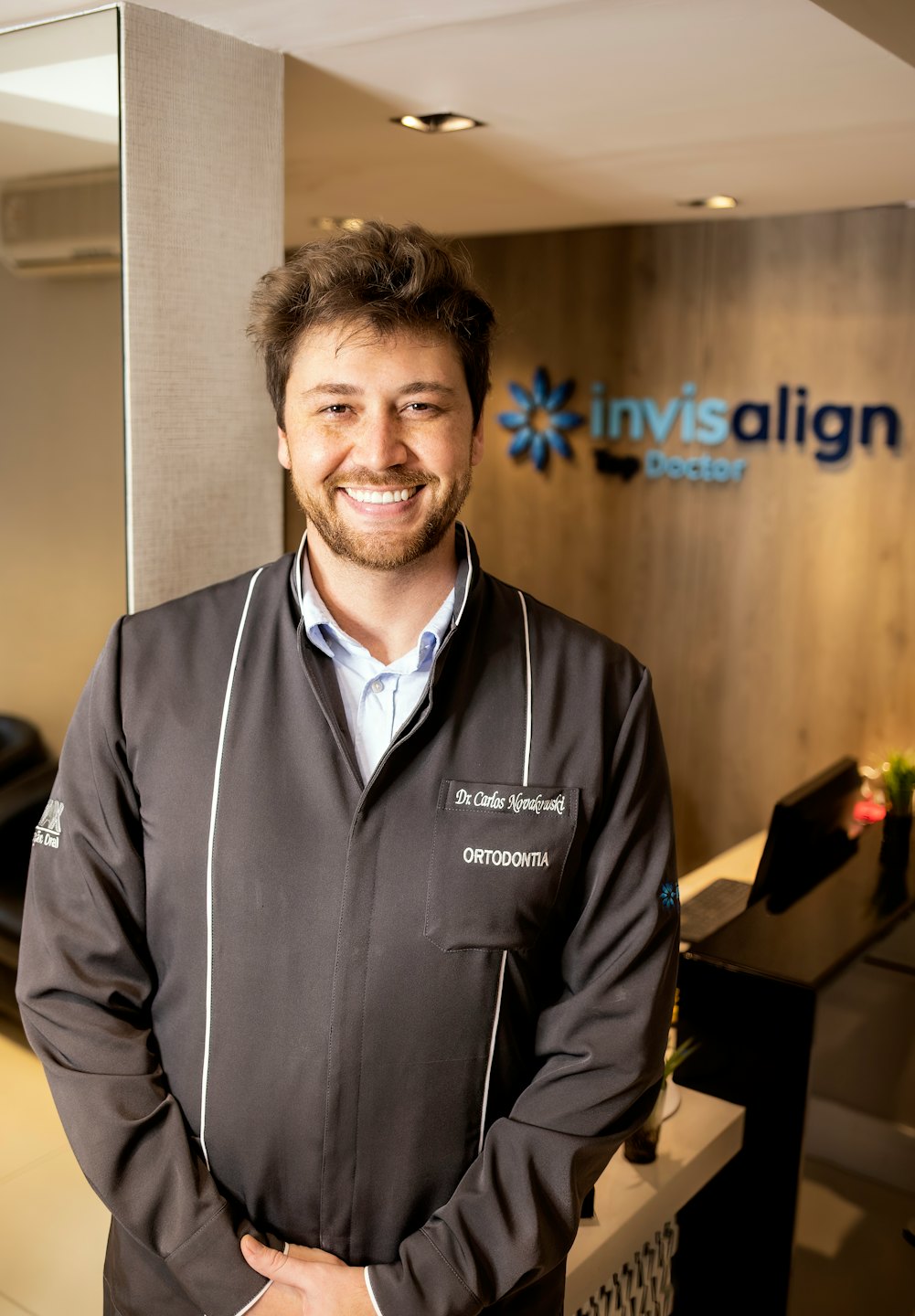 Dentista in camice grigio davanti al logo Invisalign.