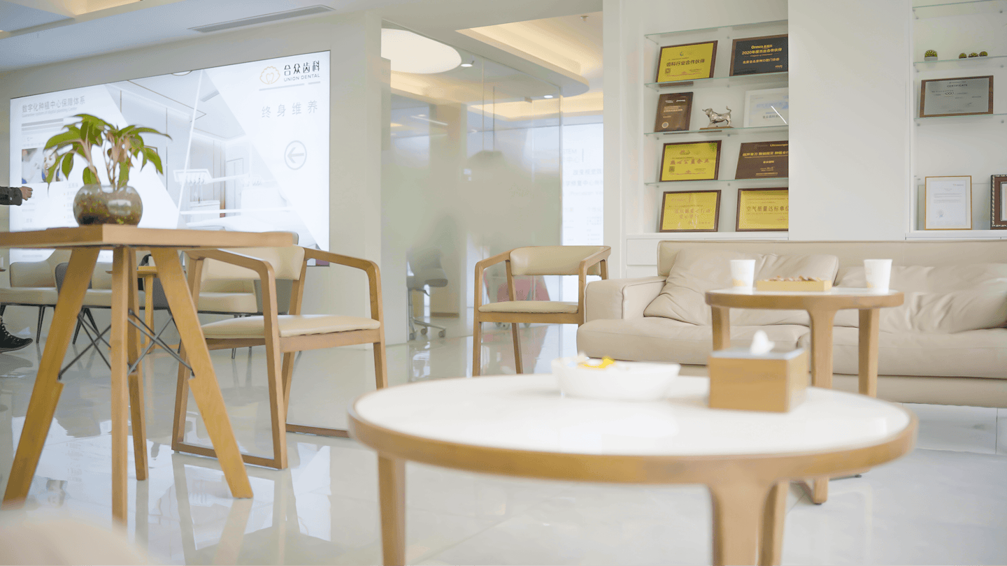 Sala d'attesa moderna e professionale con sedie e divano beige.