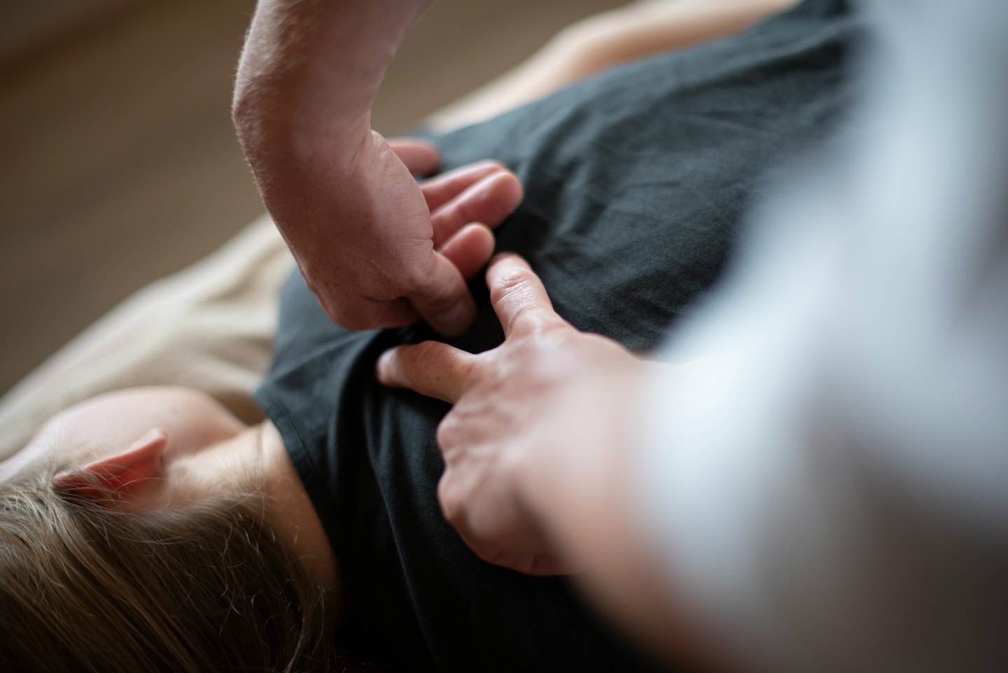 Mani che eseguono un aggiustamento terapeutico sulla parte superiore della schiena di una persona.